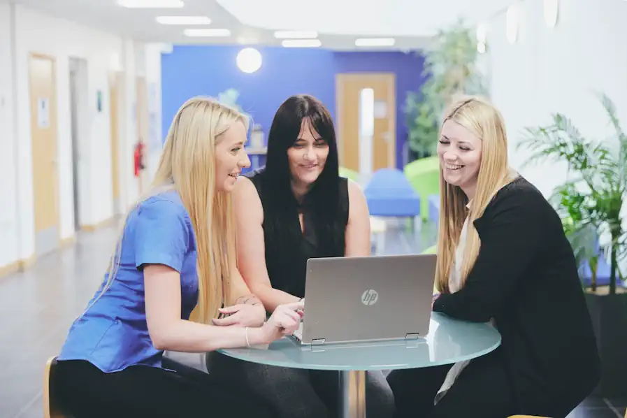 3 Blossom carers at a table around a laptop to show care worker's week.
