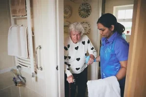 Blossom Healthcare staff helping an elderly female patient with personal care.