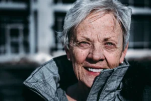 An older woman wearing a grey coat to show Blossom's dementia support.