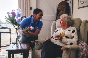 A Blossom carer helps a client to arrange flowers in their own home.