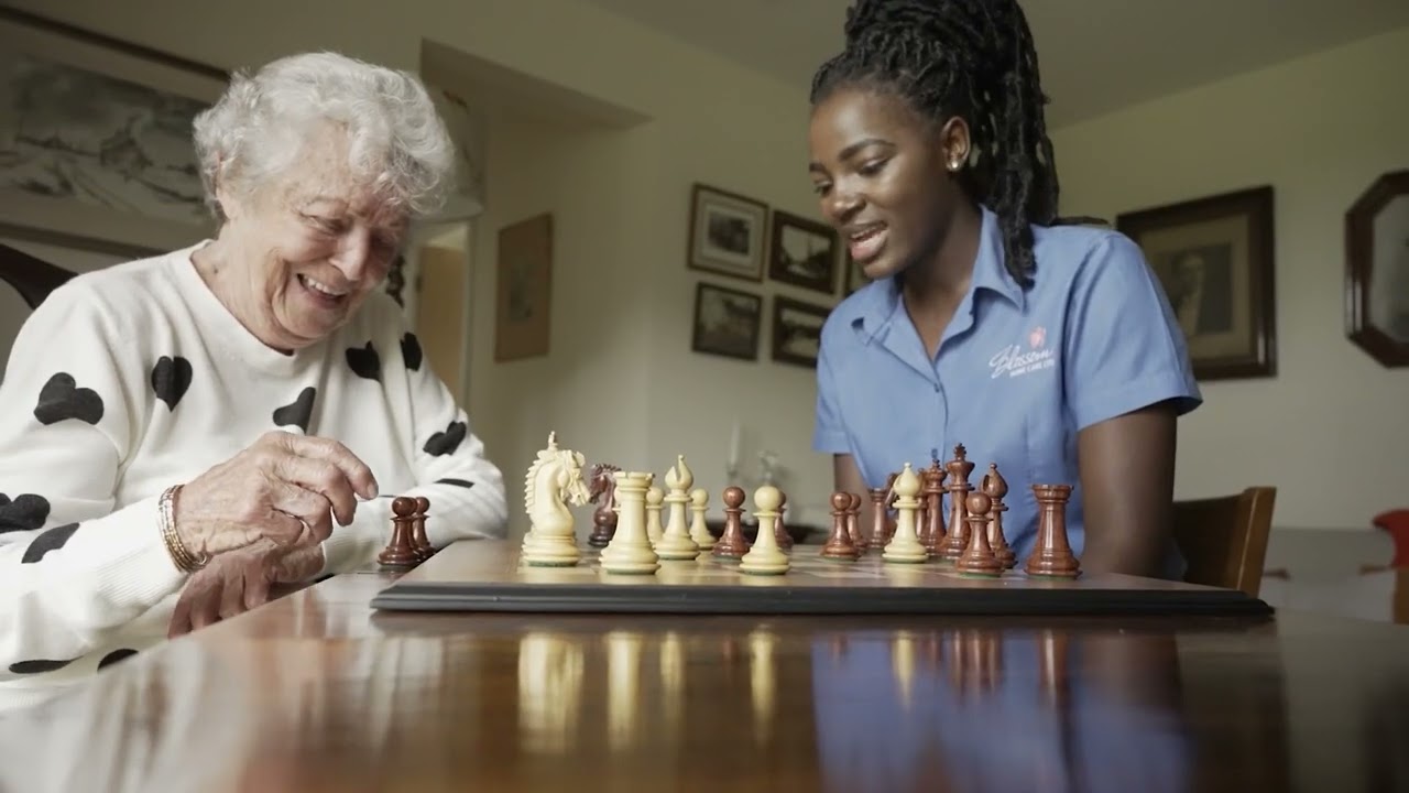 Home carer playing chess with elderly patient.