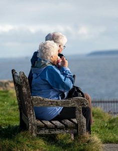 Senior people sit on a bench together.