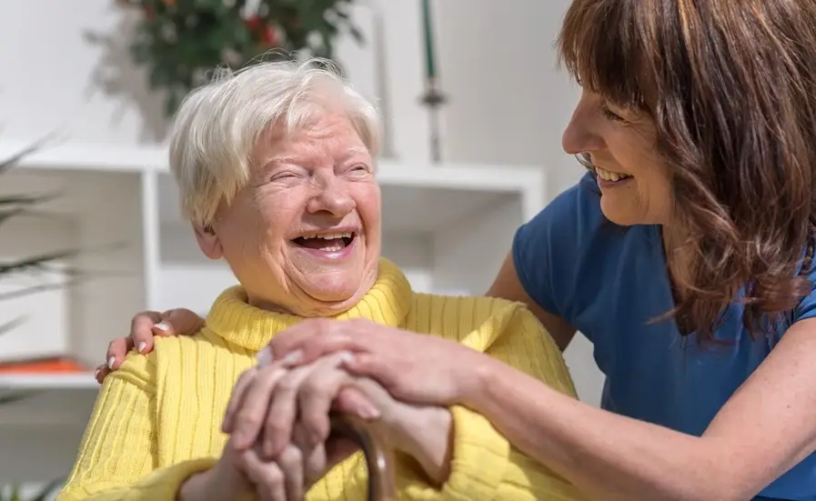 A Blossom live-in home carer embracing a smiling older woman.