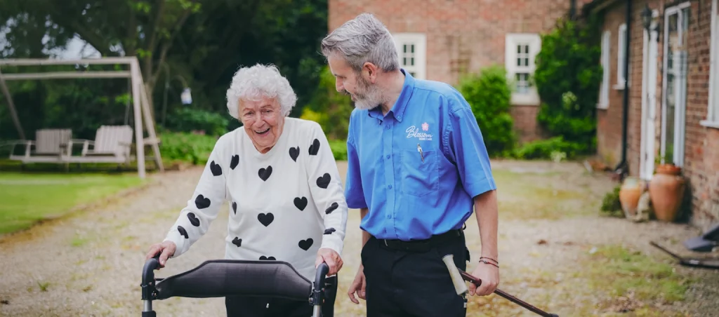 A carer walking with an elderly woman.