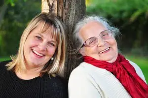 Two women smiling to show support for a loved one in a care home.