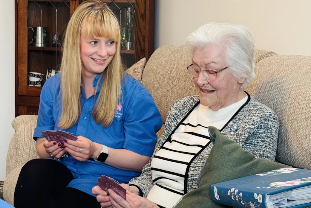 A Blossom carer plays cards with an elderly client, enriching their home experience.