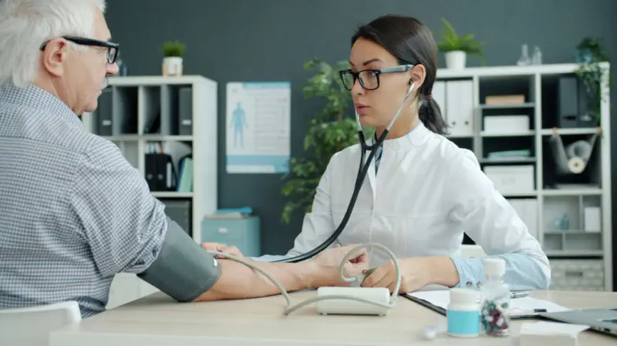 A doctor measures the blood pressure of an elderly man.