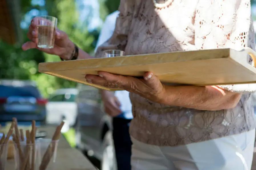 An elderly woman holds a tray of water.
