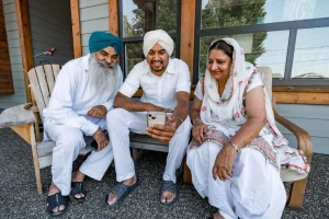 Two Asian men and one Asian woman smile at a mobile phone.