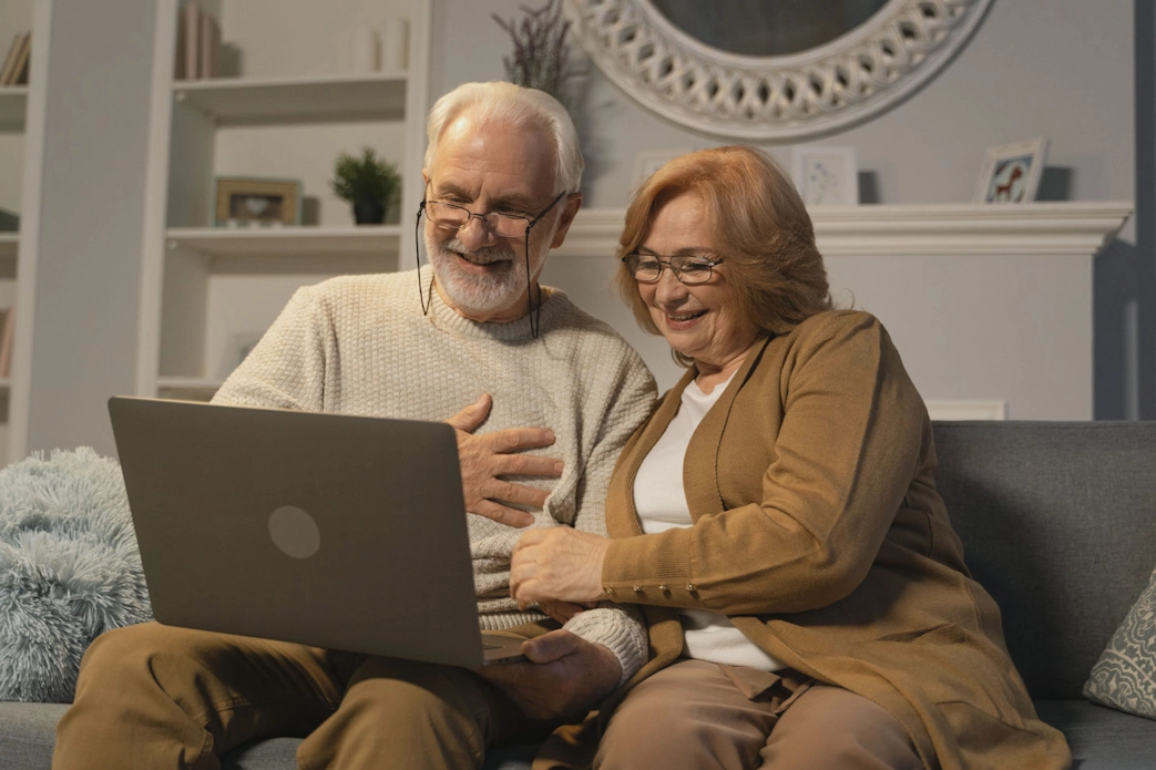 An elderly couple using their laptop for a video call.