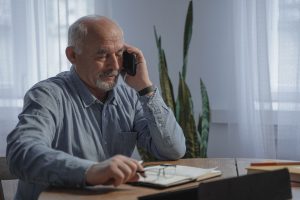 An elderly man listens to a mobile phone.